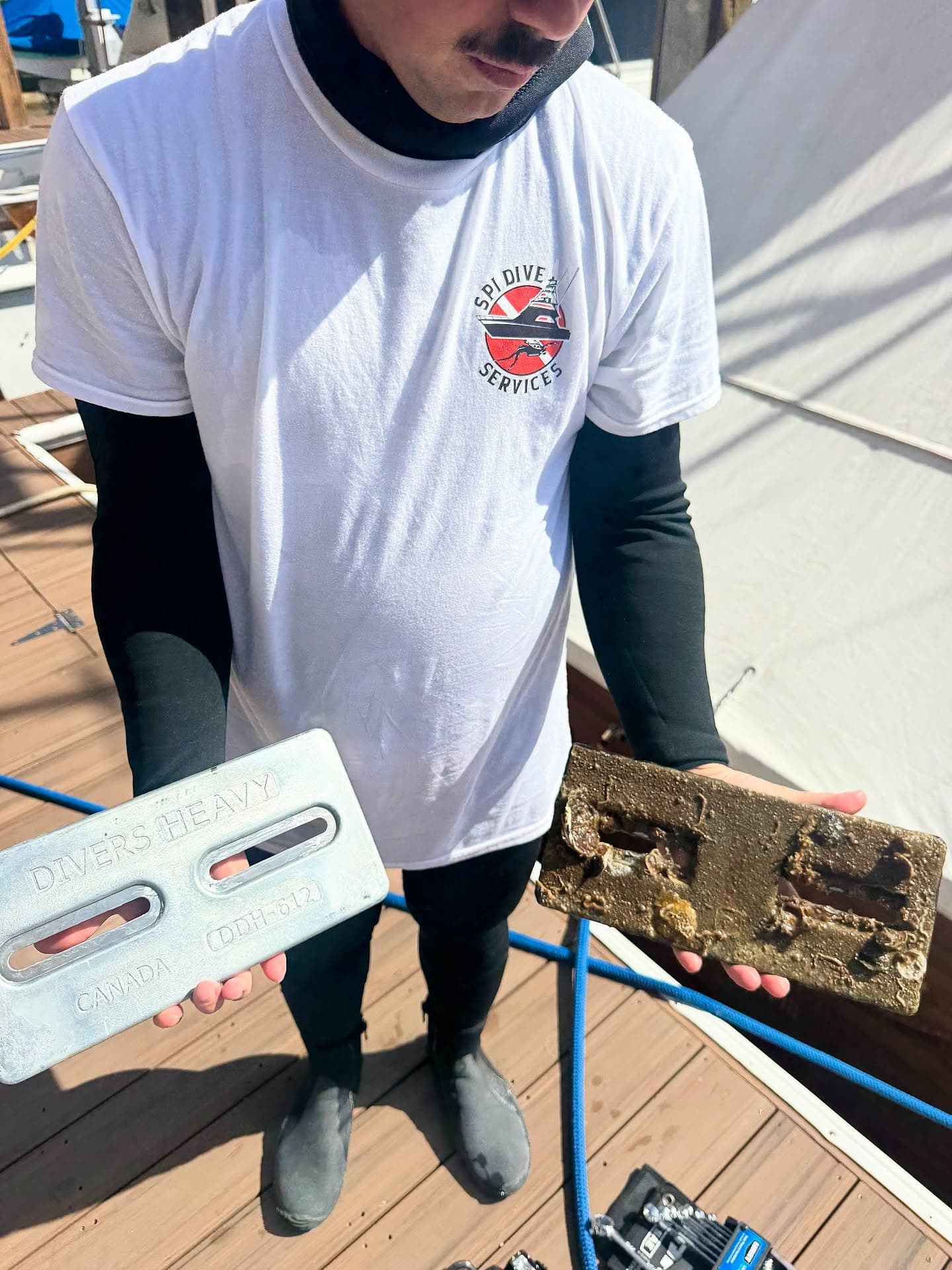 SPI Dive Services diver holds a clean replacement anode beside a heavily corroded anode removed from a boat.